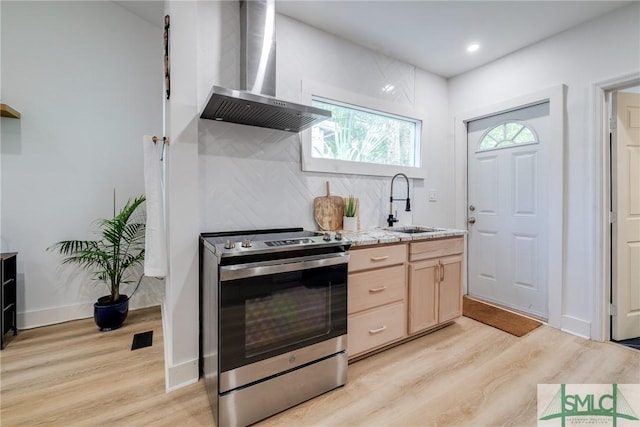 kitchen with electric range, a sink, wall chimney range hood, light brown cabinetry, and tasteful backsplash