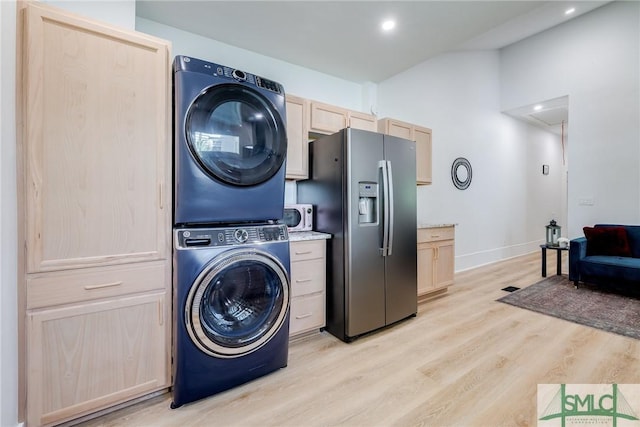 washroom featuring light wood-style flooring, laundry area, baseboards, stacked washer / drying machine, and attic access