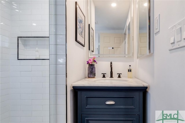 bathroom with a tile shower and vanity