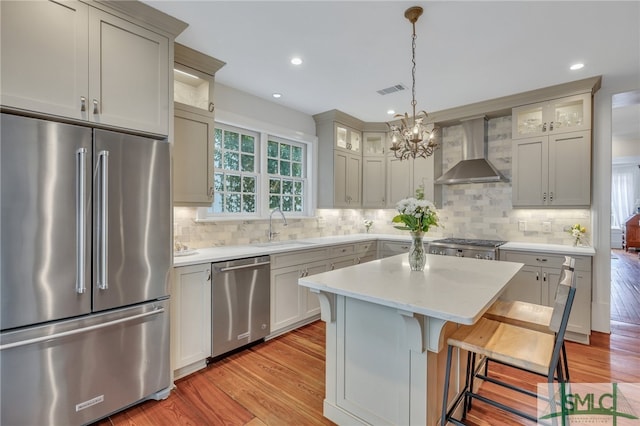 kitchen featuring stainless steel appliances, light hardwood / wood-style floors, wall chimney exhaust hood, and sink