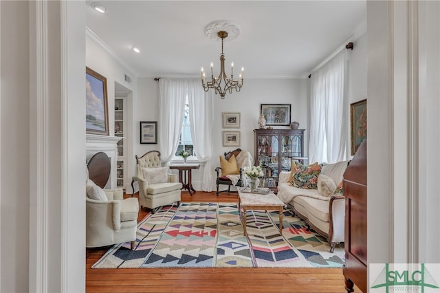 living area featuring ornamental molding, hardwood / wood-style flooring, and a chandelier