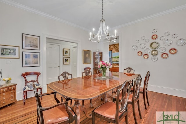 dining space featuring ornamental molding, a notable chandelier, and light wood-type flooring