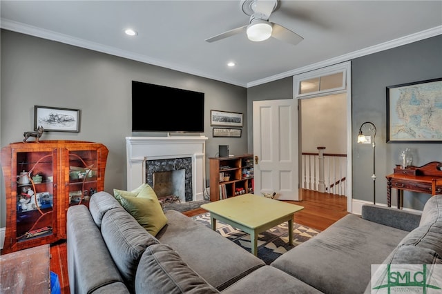 living room featuring wood-type flooring, a high end fireplace, crown molding, and ceiling fan