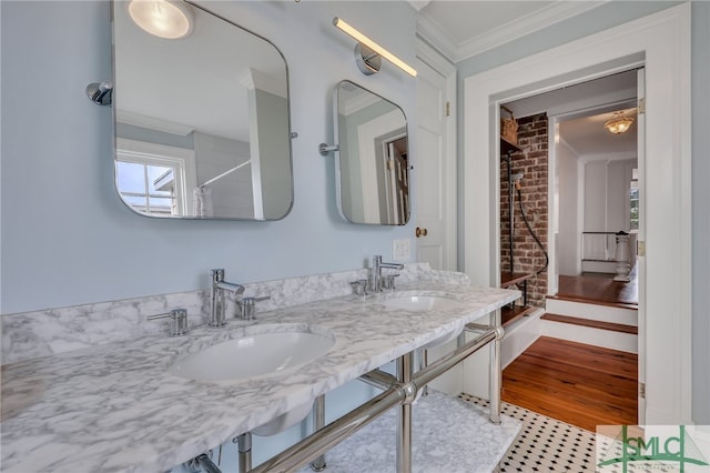 bathroom with walk in shower, crown molding, hardwood / wood-style floors, brick wall, and vanity