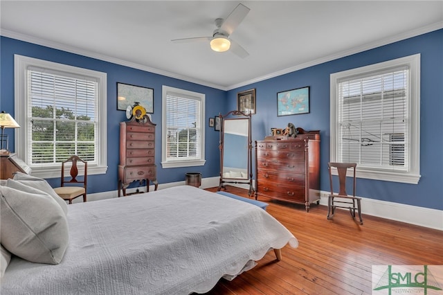 bedroom with ornamental molding, hardwood / wood-style flooring, multiple windows, and ceiling fan