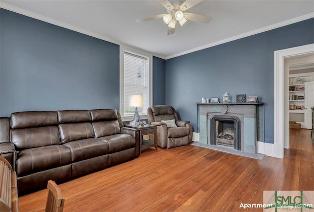 living room with wood-type flooring, ornamental molding, and ceiling fan