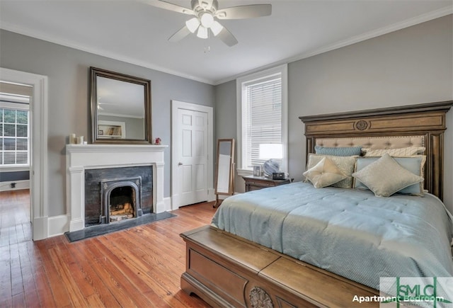 bedroom with wood-type flooring, crown molding, multiple windows, and ceiling fan