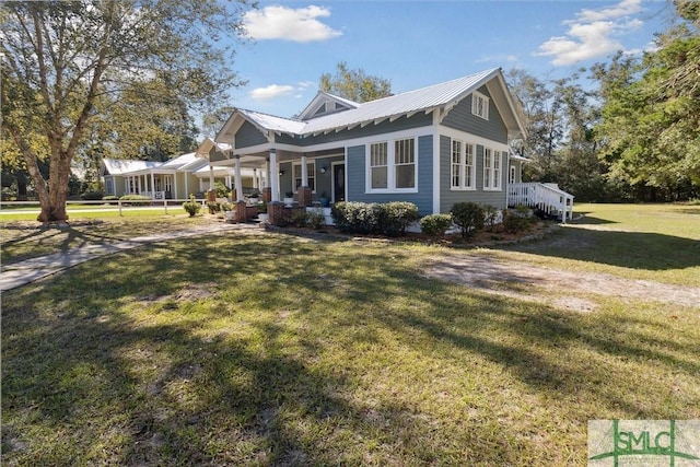 view of front of property featuring metal roof, a front lawn, and covered porch
