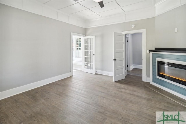 unfurnished living room featuring a glass covered fireplace, baseboards, a ceiling fan, and wood finished floors