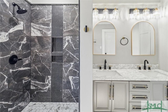 full bath featuring tiled shower, double vanity, and a sink