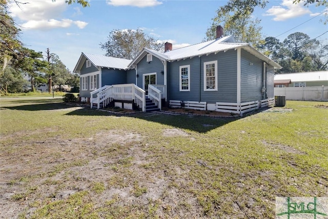 rear view of property featuring cooling unit, a chimney, metal roof, and fence
