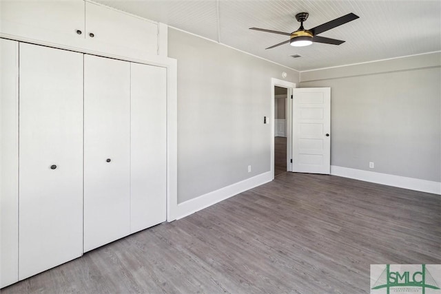 unfurnished bedroom with a closet, a ceiling fan, visible vents, wood finished floors, and baseboards