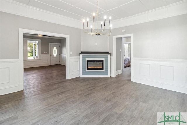 unfurnished living room featuring a decorative wall, an inviting chandelier, and wood finished floors