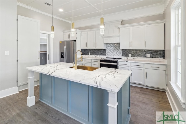 kitchen with a kitchen island with sink, decorative light fixtures, sink, stainless steel appliances, and white cabinetry