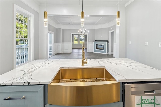 kitchen with a chandelier, open floor plan, crown molding, light stone countertops, and wood finished floors
