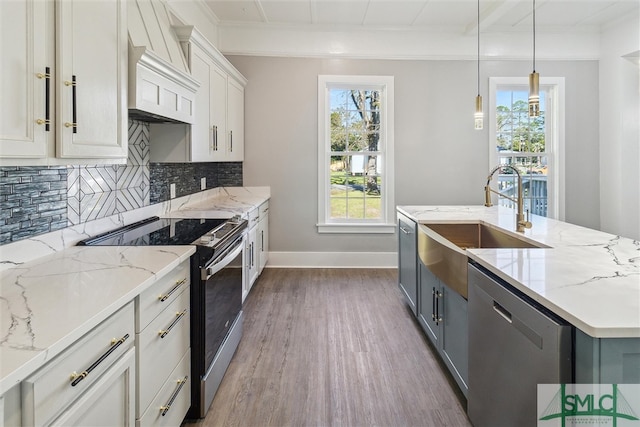 kitchen featuring hardwood / wood-style floors, light stone countertops, hanging light fixtures, white cabinets, and appliances with stainless steel finishes