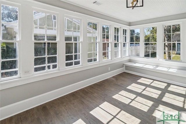 unfurnished sunroom featuring wood finished floors, baseboards, visible vents, and a healthy amount of sunlight