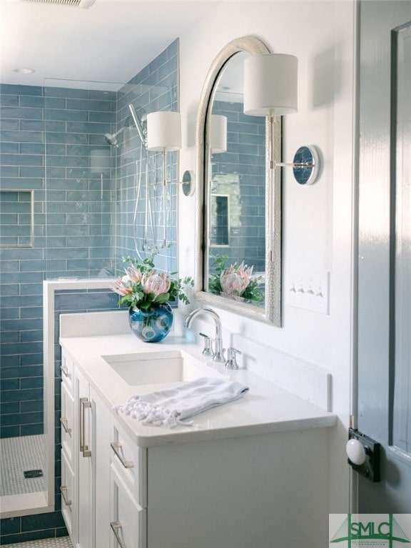 bathroom featuring tile patterned floors, tiled shower, and vanity