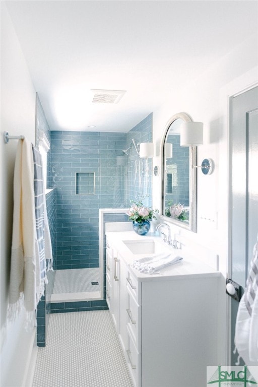 bathroom featuring tile patterned floors, a tile shower, and vanity