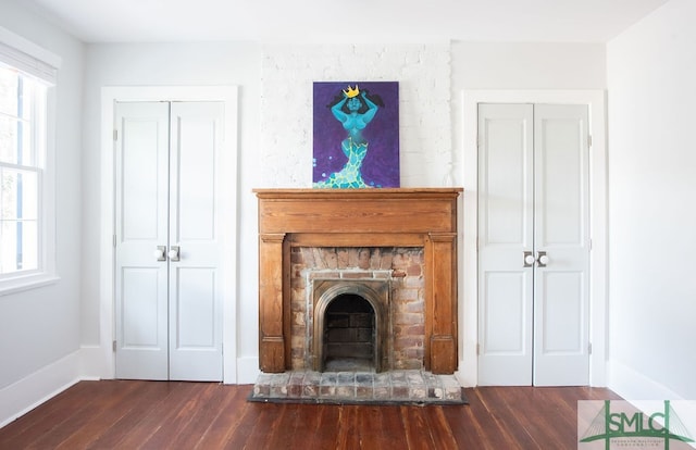 unfurnished living room featuring a brick fireplace and dark hardwood / wood-style flooring