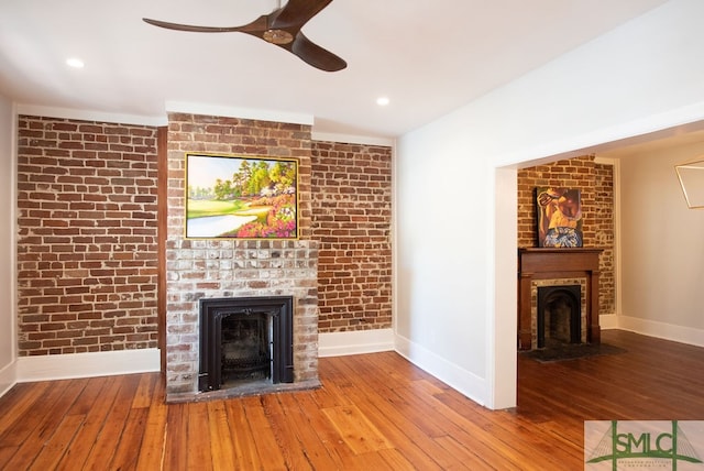 unfurnished living room featuring a brick fireplace, brick wall, and light wood-type flooring