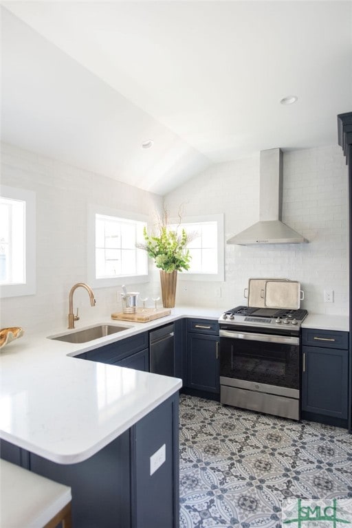 kitchen with appliances with stainless steel finishes, wall chimney exhaust hood, kitchen peninsula, and a wealth of natural light