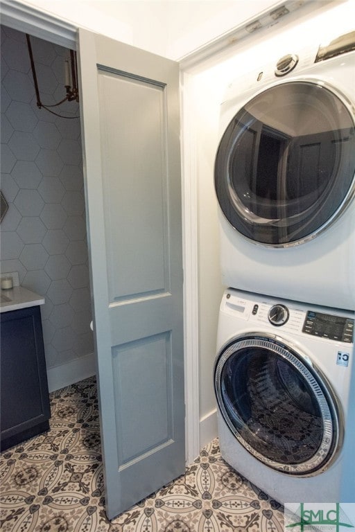 laundry room with stacked washer and dryer and light tile patterned floors