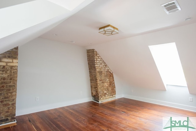 additional living space with hardwood / wood-style flooring and vaulted ceiling with skylight