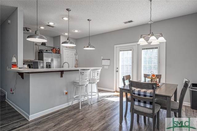 dining room with a textured ceiling, sink, and dark wood-type flooring