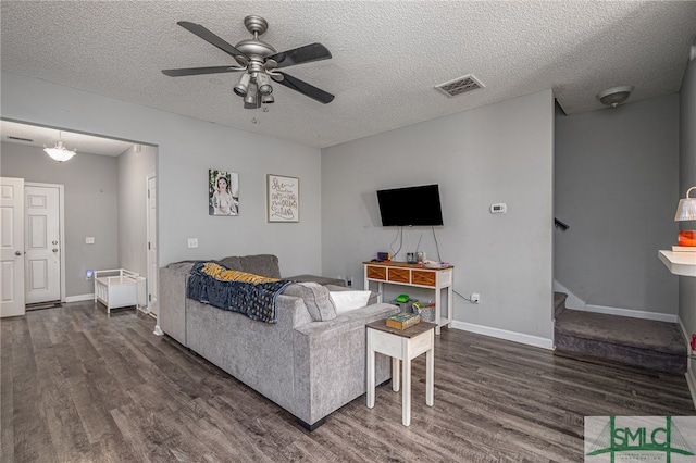 living room featuring ceiling fan, dark wood-type flooring, and a textured ceiling