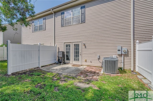 back of house with central AC unit, a lawn, and a patio area