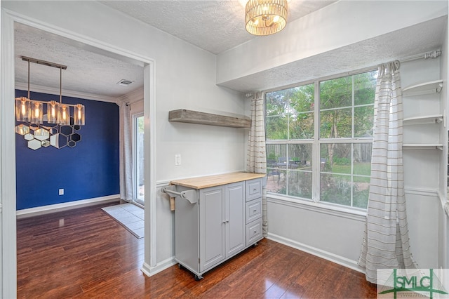 kitchen featuring a textured ceiling, a chandelier, dark wood-type flooring, pendant lighting, and butcher block countertops