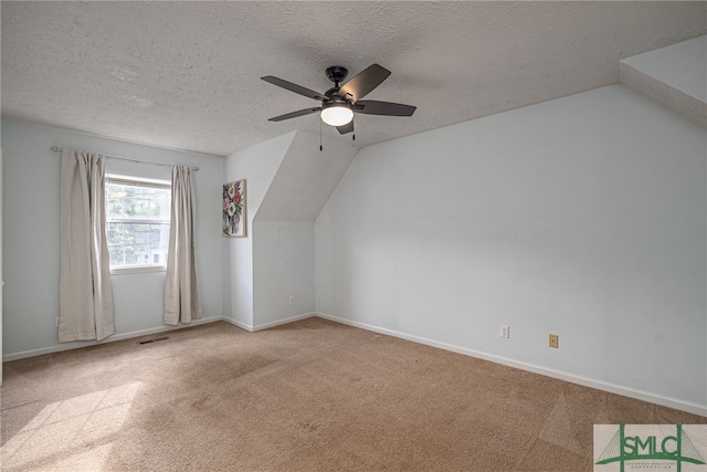 additional living space featuring vaulted ceiling, light carpet, a textured ceiling, and ceiling fan