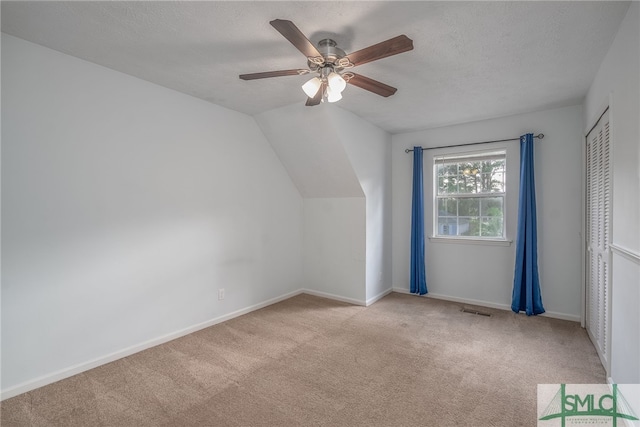 bonus room featuring vaulted ceiling, light carpet, a textured ceiling, and ceiling fan