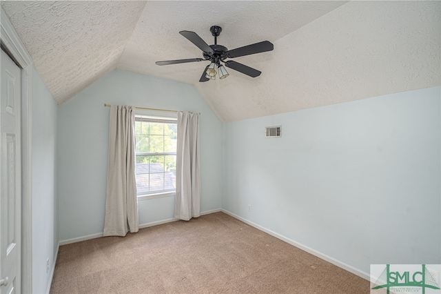 additional living space featuring lofted ceiling, a textured ceiling, light colored carpet, and ceiling fan