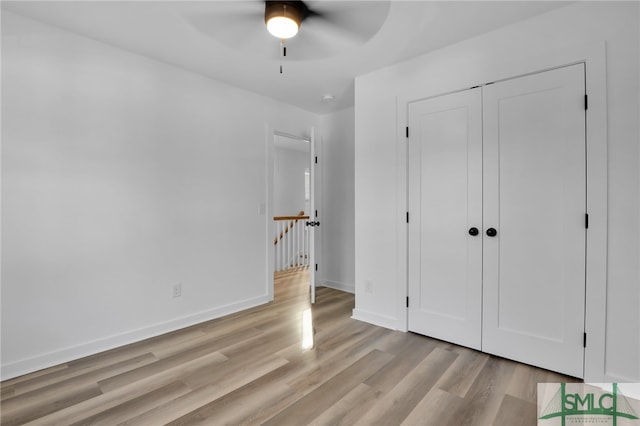 unfurnished bedroom featuring ceiling fan, light hardwood / wood-style floors, and a closet