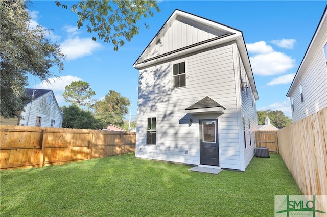 rear view of property with a lawn and central air condition unit