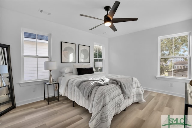 bedroom with ceiling fan, multiple windows, and light hardwood / wood-style flooring