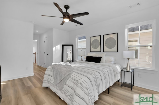 bedroom with ceiling fan, multiple windows, and light hardwood / wood-style flooring