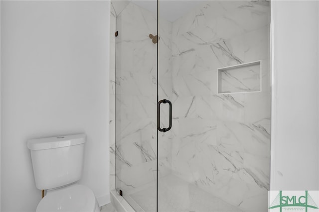 bathroom featuring toilet and a shower with shower door