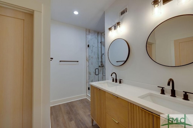 bathroom featuring hardwood / wood-style floors, vanity, and a shower with shower door