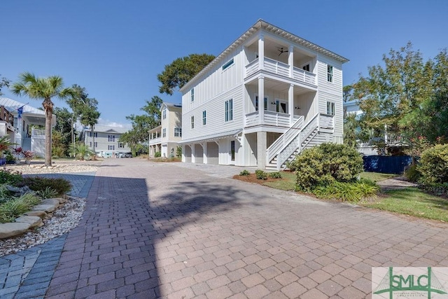 4 River Oak Ln, Tybee Island, GA 31328 - view of front of property with a balcony, stairs, decorative driveway, a ceiling fan, and board and batten siding