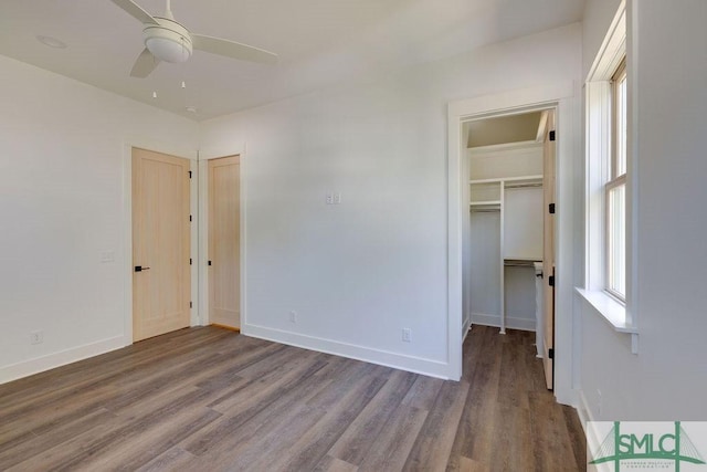 unfurnished bedroom with hardwood / wood-style flooring, a spacious closet, and ceiling fan