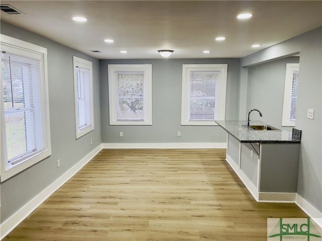 kitchen featuring a healthy amount of sunlight, sink, light wood-type flooring, and a breakfast bar