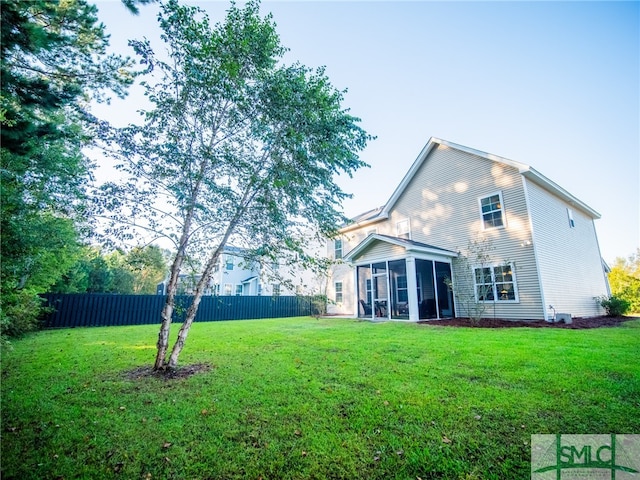 rear view of property featuring a lawn and a sunroom