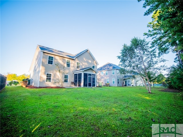 rear view of property with a sunroom and a lawn