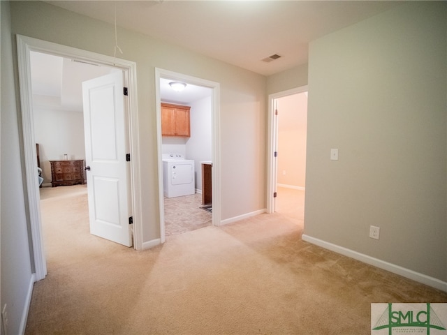 hallway with washer / clothes dryer and light colored carpet