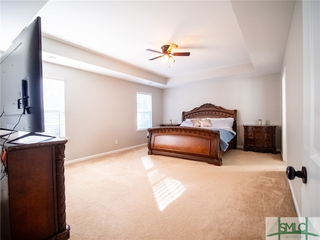 carpeted bedroom with ceiling fan and a tray ceiling