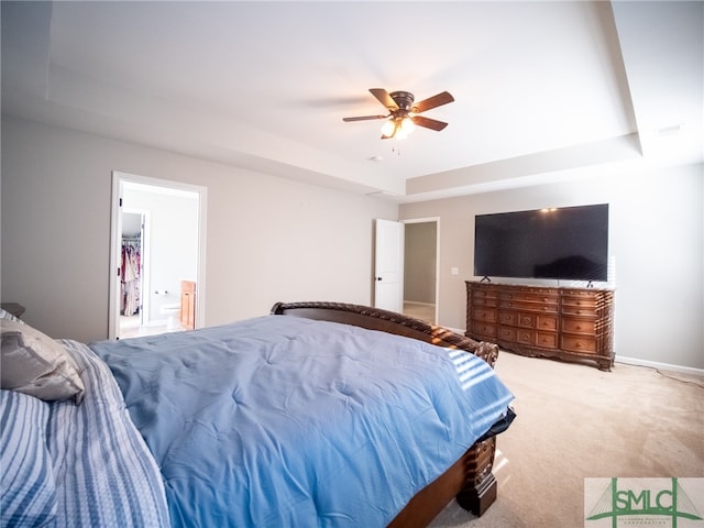 carpeted bedroom featuring ceiling fan, a raised ceiling, and ensuite bathroom