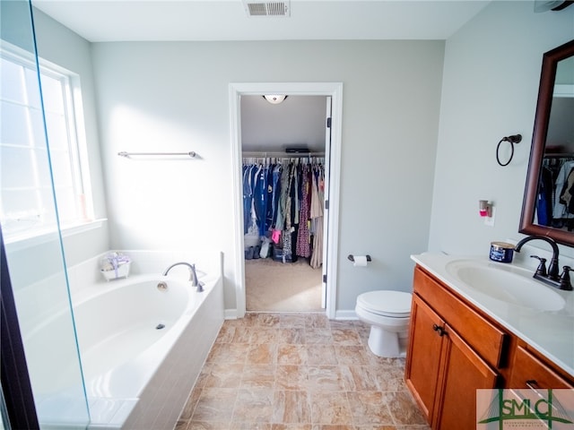 bathroom featuring vanity, a relaxing tiled tub, and toilet